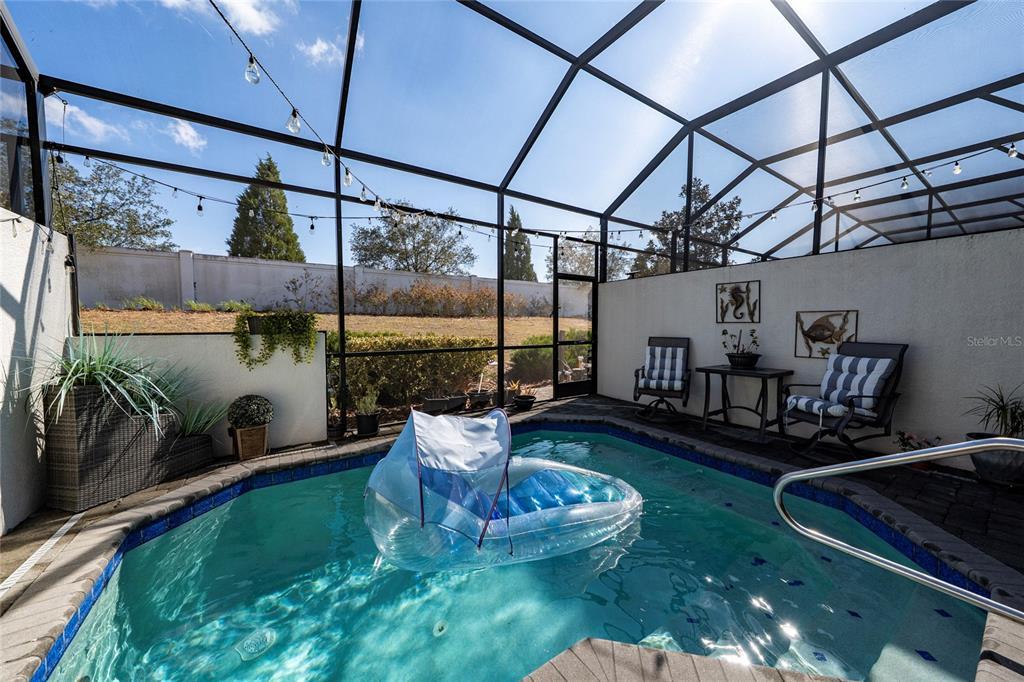 A screened-in patio features a small swimming pool with a floating lounge chair — 282 CAPTIVA DRIVE, DAVENPORT, FL