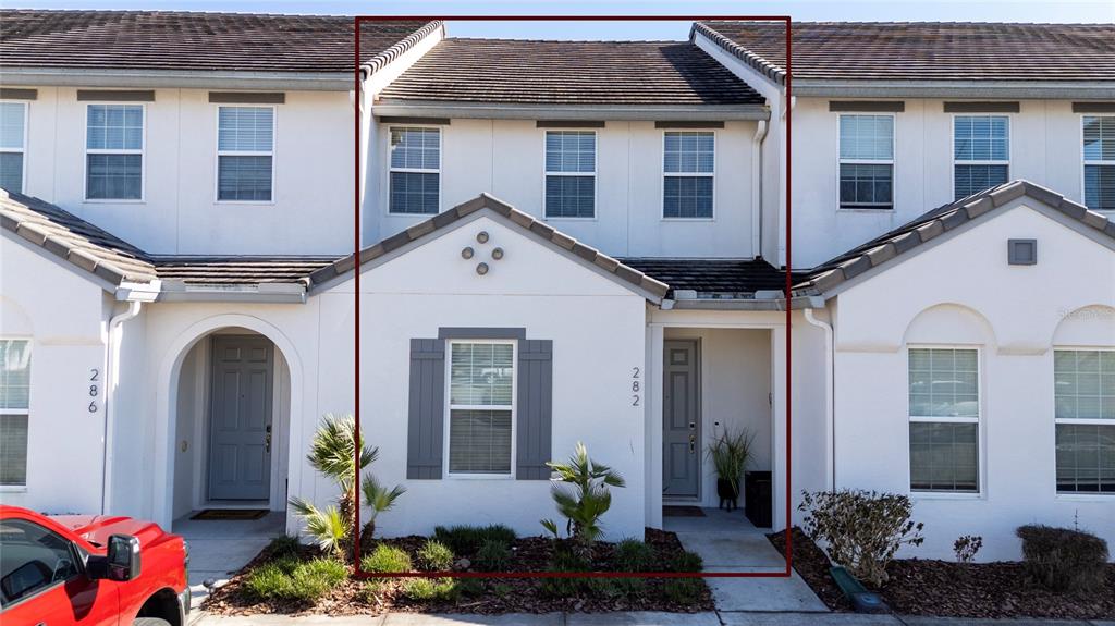 A two-story townhouse exterior features white stucco walls, a brown shingled roof, and shutters — 282 CAPTIVA DRIVE, DAVENPORT, FL