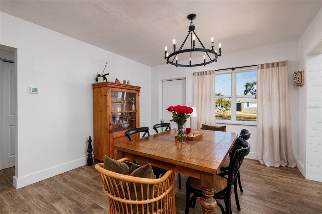 A dining room features a wooden table, black chairs, a hutch, and a chandelier — 600 74TH AVENUE N, ST PETERSBURG, FL