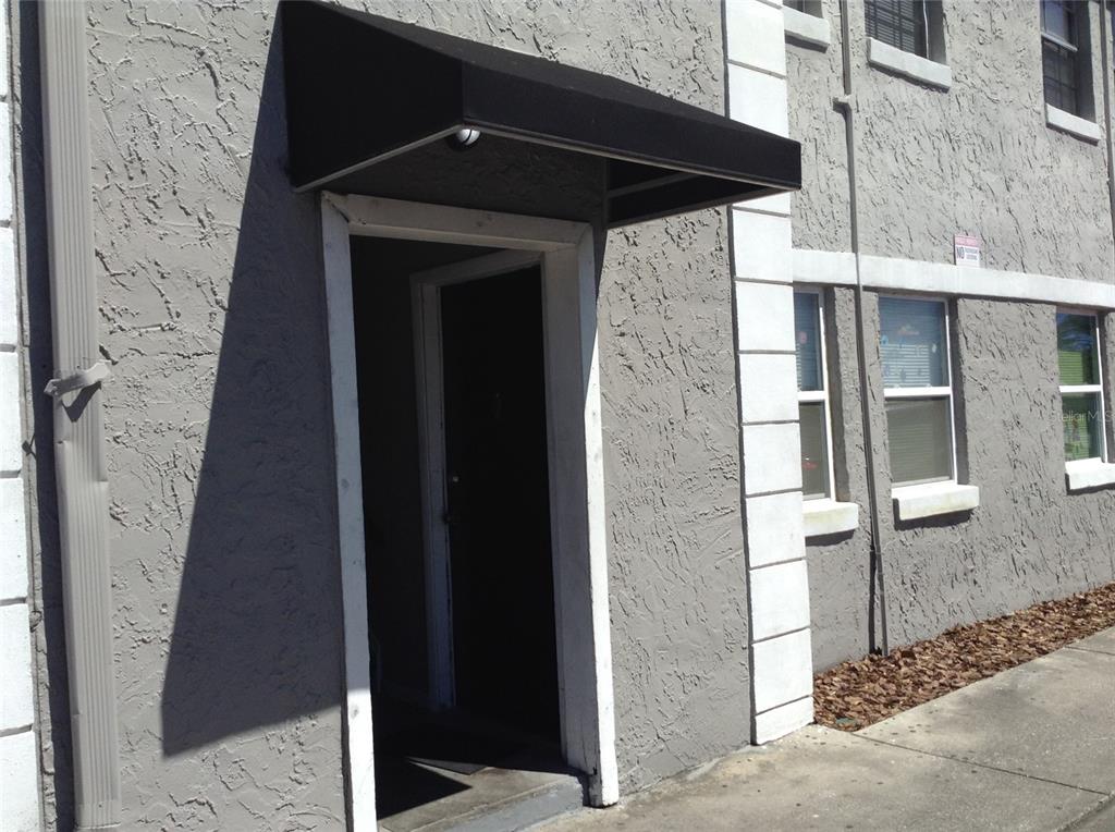 A gray stucco building exterior features a black fabric awning over a dark entry door — 2791 L B MCLEOD ROAD UNIT 2791B, ORLANDO, FL