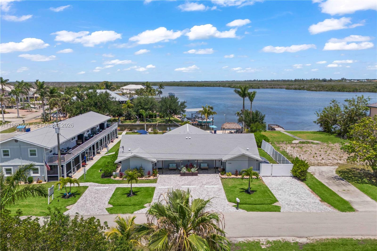 An aerial view shows a gray house with a paved driveway near a waterfront — 12200/12210 Shoreview DR, Matlacha FL 33993, MATLACHA, FL