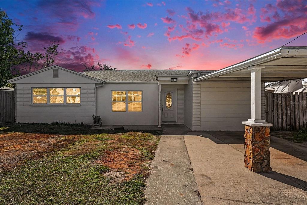 A single-story white house with a carport and a stone-based pillar at sunset — 2910 W BURKE STREET, TAMPA, FL
