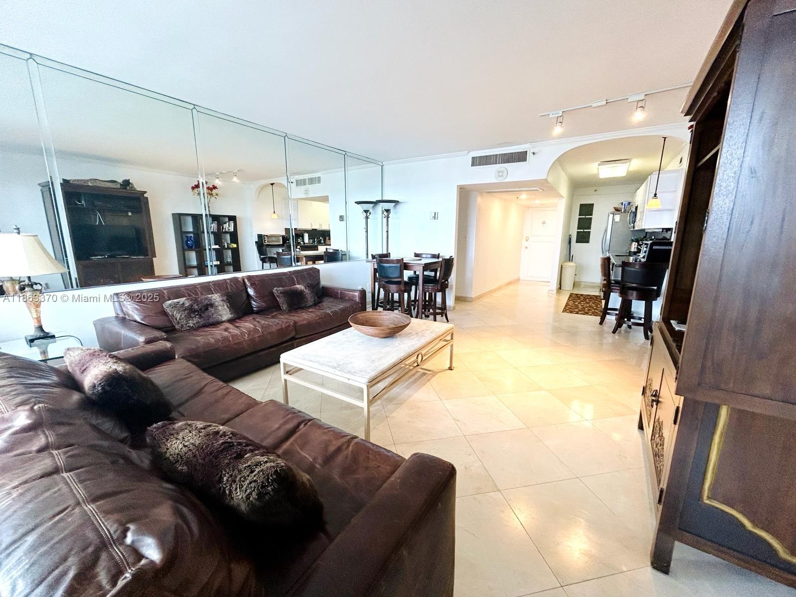 A living room features brown leather sofas, a marble coffee table, and a mirrored wall — 100 Lincoln Rd # 1034, Miami Beach FL 33139, MIAMI BEACH, FL