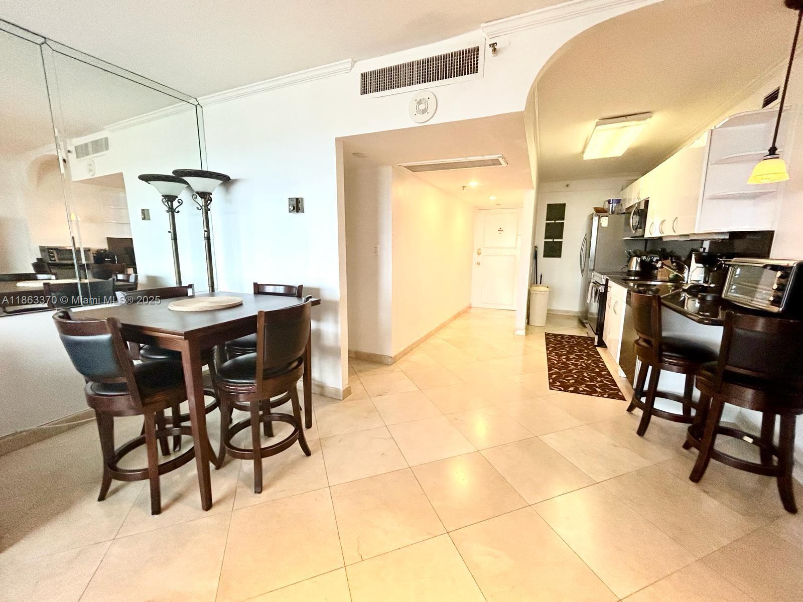 A dining area with a table and chairs sits adjacent to a galley-style kitchen — 100 Lincoln Rd # 1034, Miami Beach FL 33139, MIAMI BEACH, FL