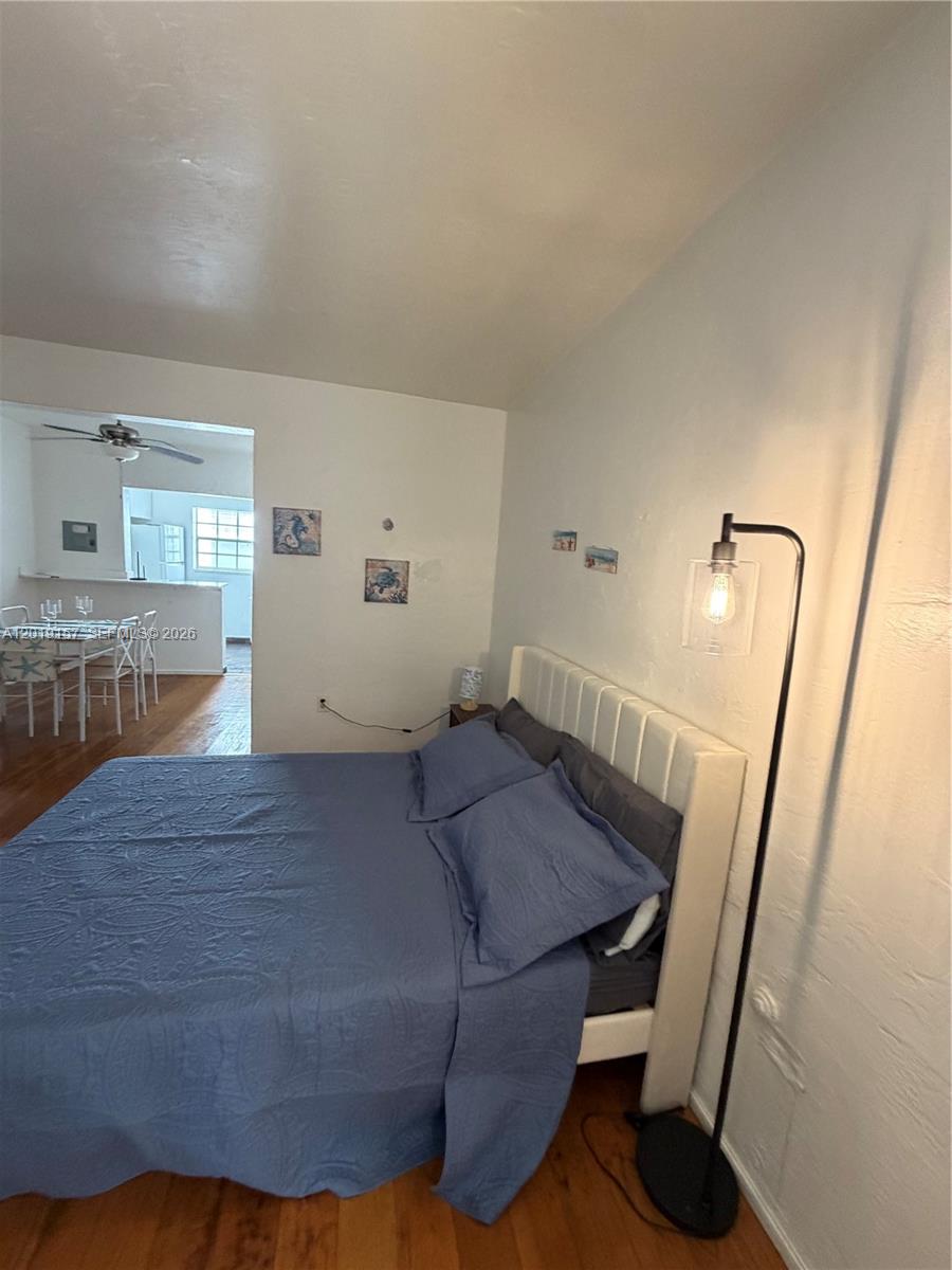 A bedroom features a white bed frame, blue bedding, and a floor lamp — MIAMI BEACH, FL