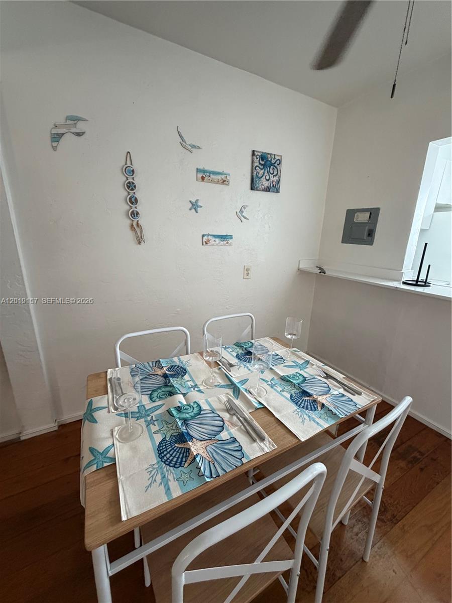 A dining area features a wooden table with four chairs and beach-themed wall decor — MIAMI BEACH, FL