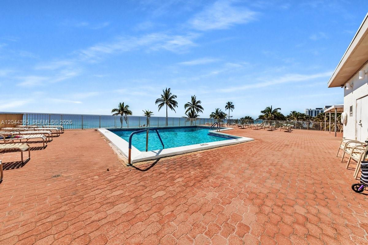 An outdoor swimming pool area with lounge chairs on a brick patio overlooking the ocean — 3111 N Ocean Dr # 904, Hollywood FL 33019, HOLLYWOOD, FL