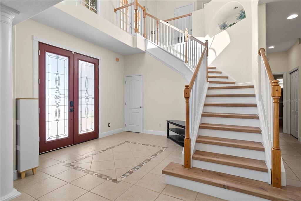 A foyer features a red double front door, tiled floor, and a wooden staircase — 16727 ROYAL PALM DRIVE, GROVELAND, FL