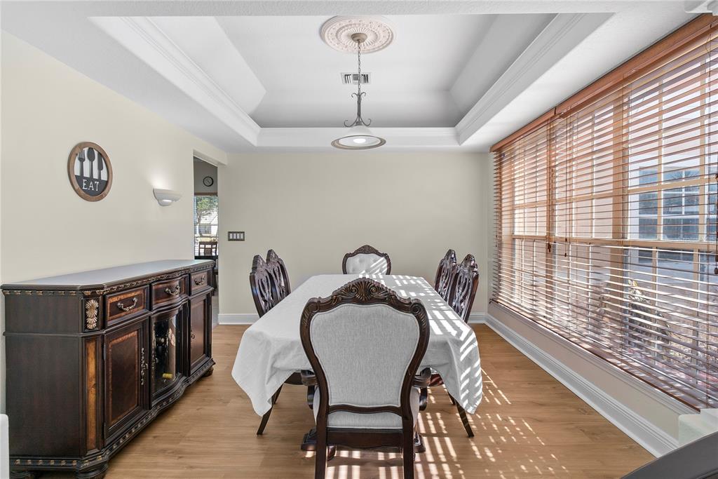 A dining room features a tray ceiling, a wooden sideboard, and a table with chairs — 16727 ROYAL PALM DRIVE, GROVELAND, FL