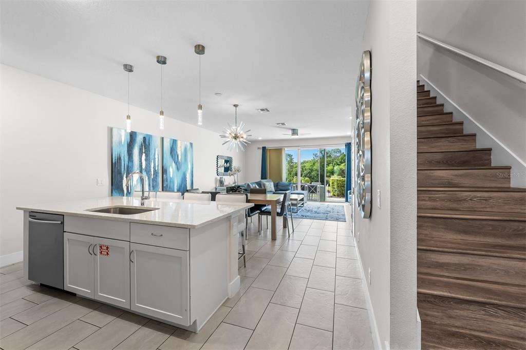 A kitchen island with a sink sits before a dining area and living room — 856 DRIVING RANGE COURT, REUNION, FL