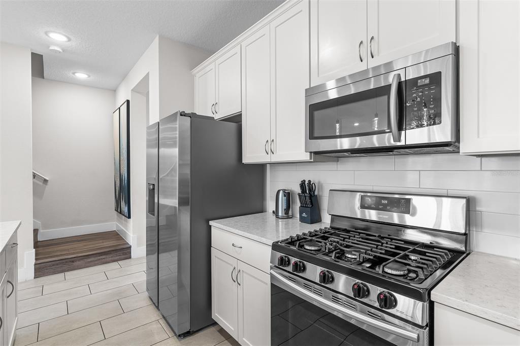 A kitchen with white cabinets, stainless steel appliances, and light-colored tile flooring — 856 DRIVING RANGE COURT, REUNION, FL