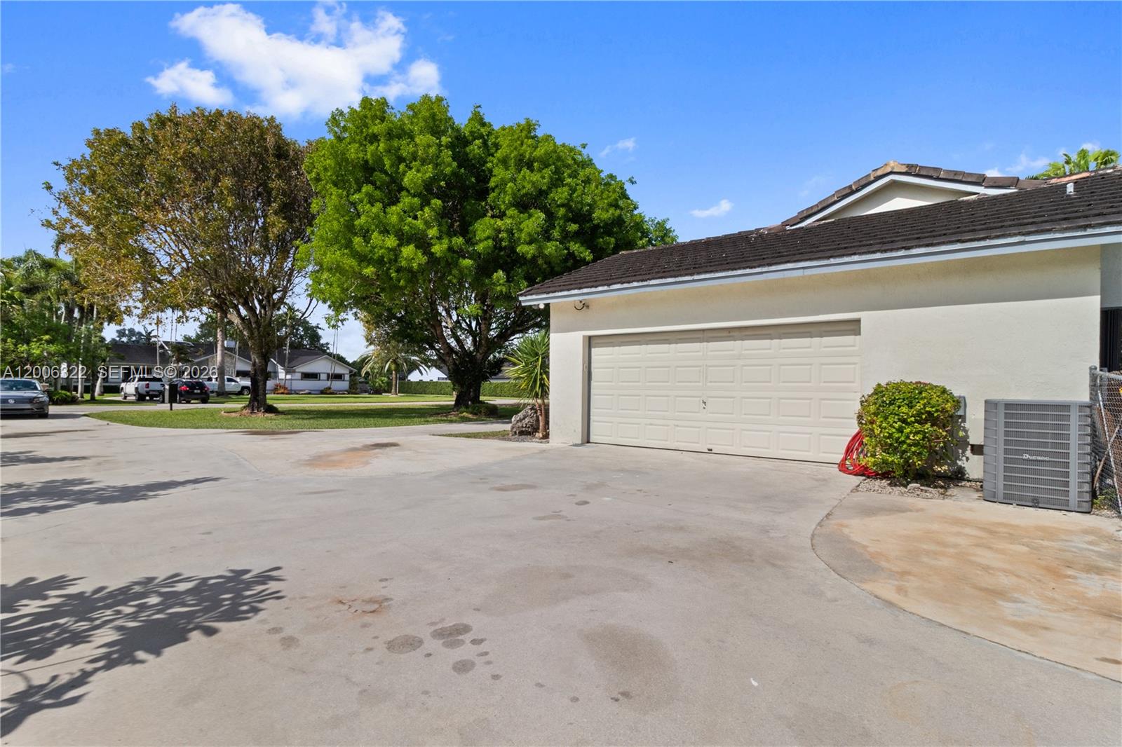 A concrete driveway leads to a two-car garage beside a house with a tiled roof — 15941 SW 252nd St, Homestead FL 33031, HOMESTEAD, FL