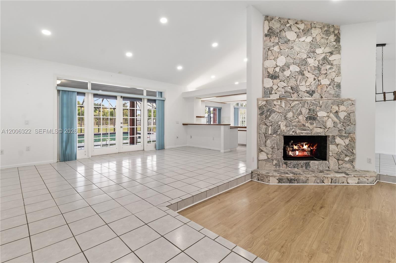 A living room features a stone fireplace, tile and wood flooring, and glass patio doors — 15941 SW 252nd St, Homestead FL 33031, HOMESTEAD, FL