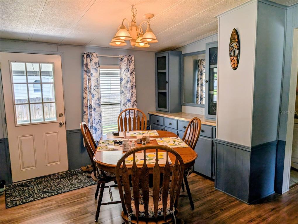 A dining area features a wooden table, four chairs, blue cabinetry, and a glass-paneled door — 9300 SE 140TH PLACE, SUMMERFIELD, FL