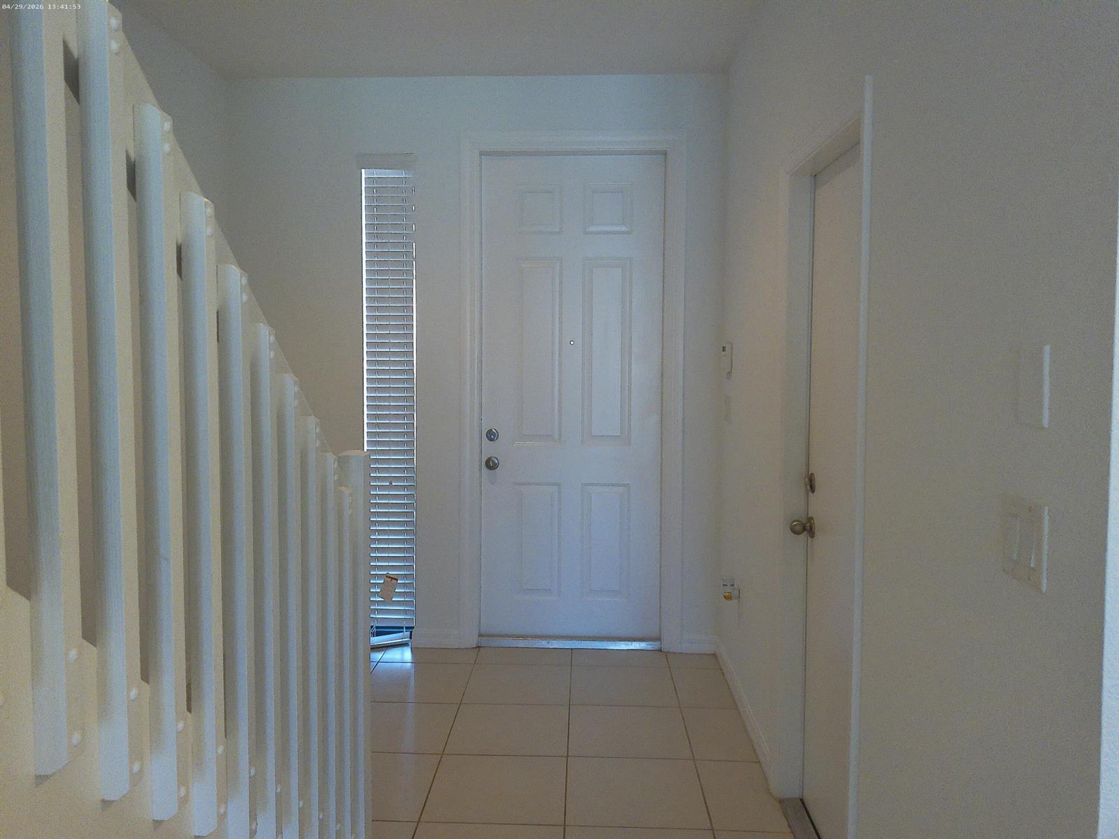 A bright entryway features white walls, tiled flooring, a front door, and a staircase railing — 1088 NW 33rd Court, Pompano Beach FL 33064, POMPANO BEACH, FL