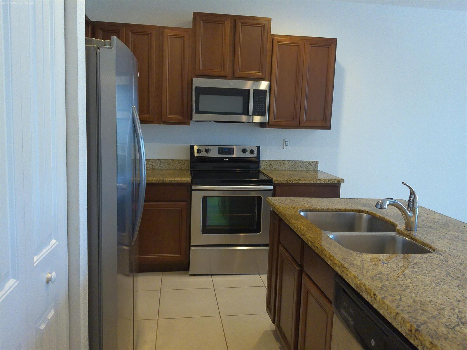 A kitchen features brown cabinets, stainless steel appliances, and granite countertops with a double sink — 1088 NW 33rd Court, Pompano Beach FL 33064, POMPANO BEACH, FL