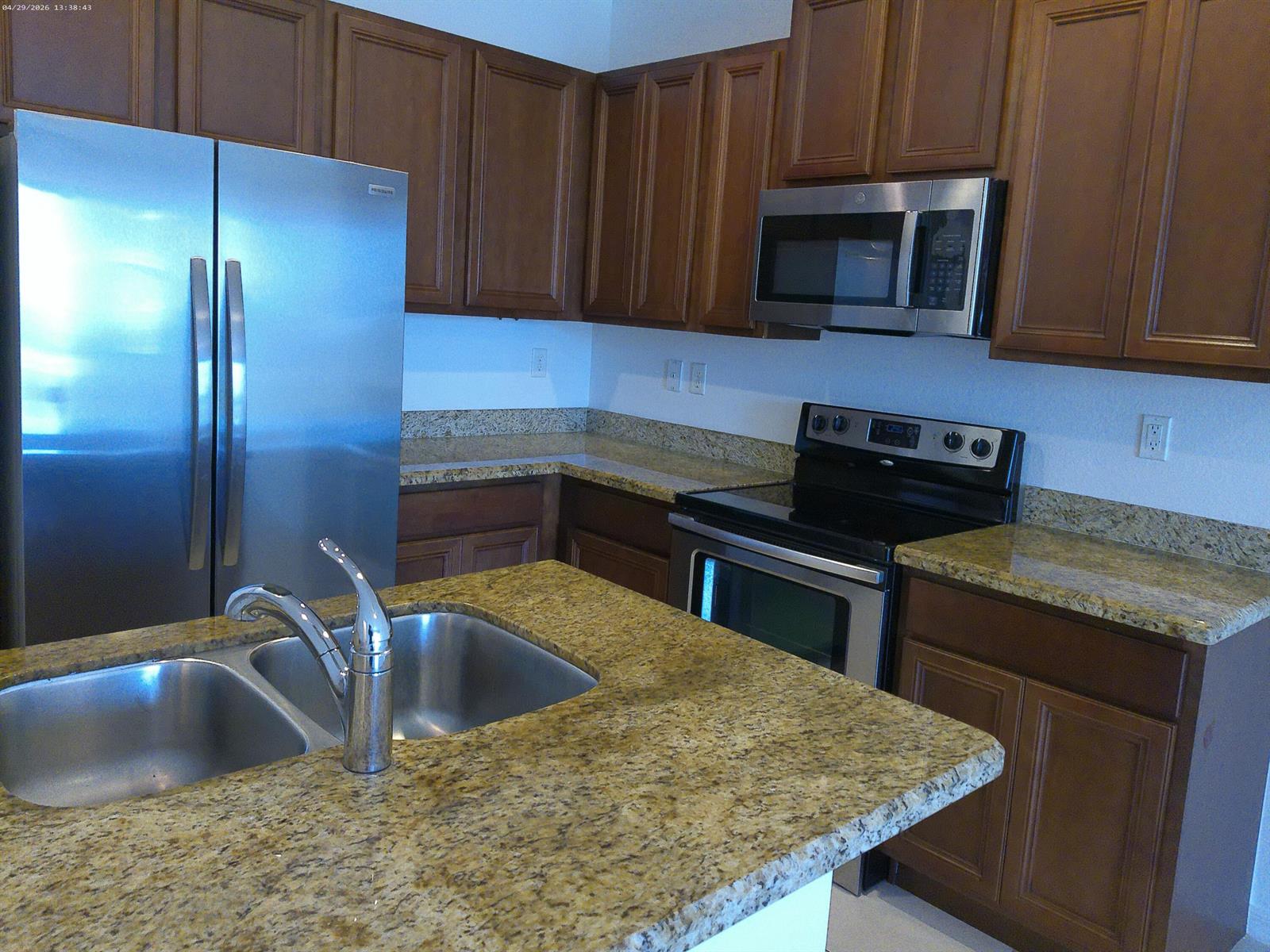 A kitchen features stainless steel appliances, wood cabinets, and granite countertops with a double sink — 1088 NW 33rd Court, Pompano Beach FL 33064, POMPANO BEACH, FL