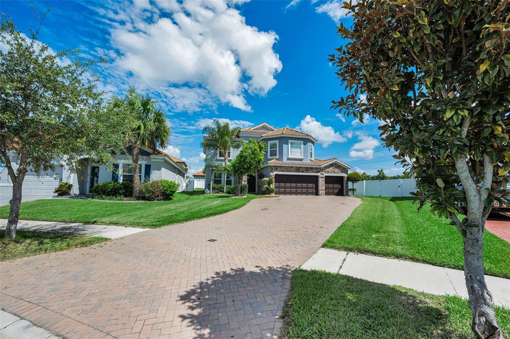 A two-story suburban house with a brick paver driveway and a three-car garage — 11923 CINNAMON FERN DRIVE, RIVERVIEW, FL