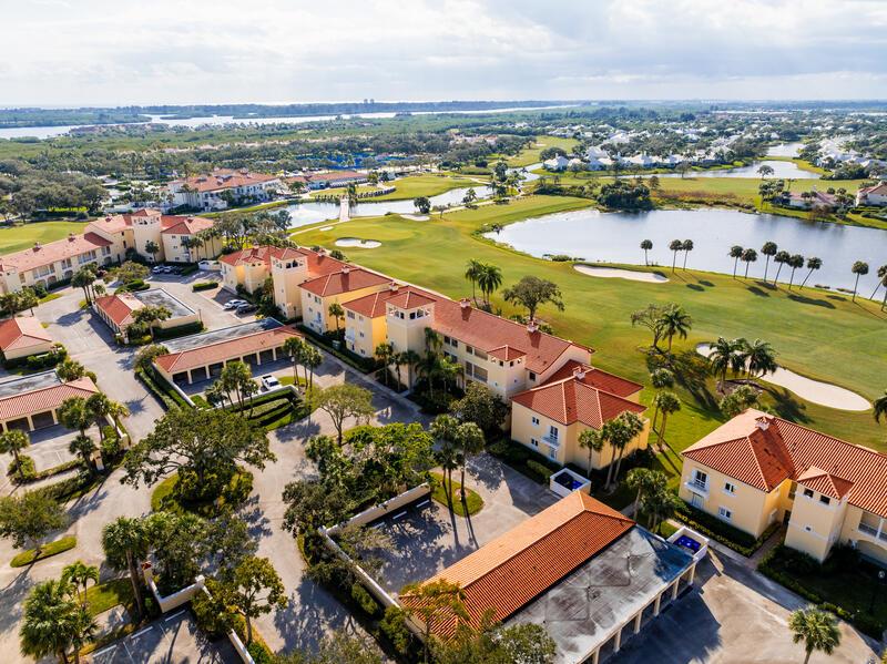An aerial view shows a multi-story residential complex situated beside a golf course and lake — VERO BEACH, FL