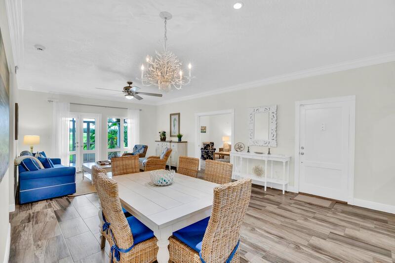 A dining area with a white table and wicker chairs sits before a living room — VERO BEACH, FL