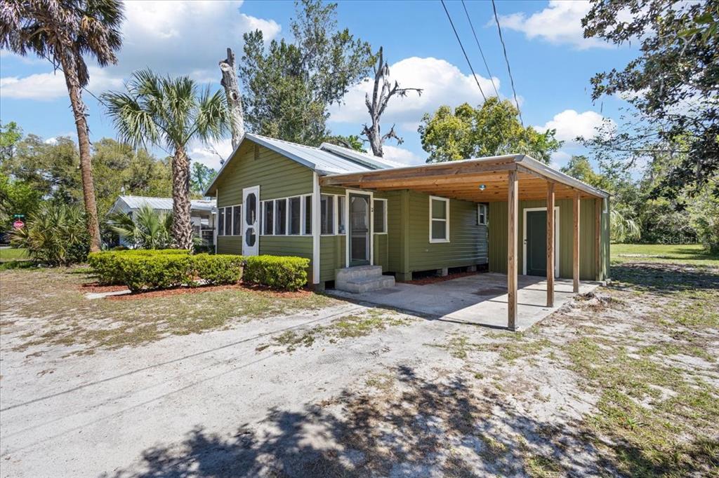 A green, single-story house with a metal roof and an attached wooden carport — 102 NE 138TH STREET, CROSS CITY, FL