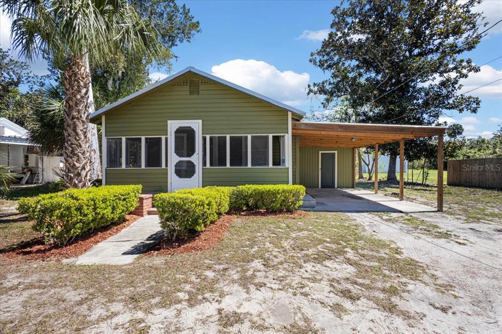 A green, single-story house features a front porch, a carport, and a palm tree — 102 NE 138TH STREET, CROSS CITY, FL