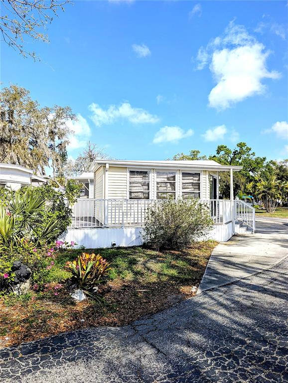 A light-colored mobile home features a white porch railing and a paved driveway — 3300 26TH AVENUE E UNIT 228, BRADENTON, FL