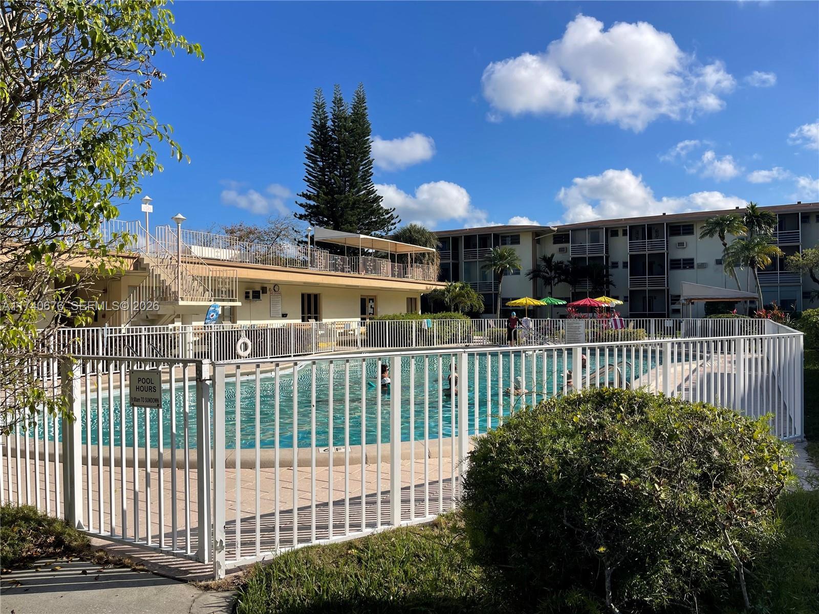 A fenced outdoor swimming pool sits in front of a multi-story apartment building — 17090 NE 14th Ave # 314, Miami FL 33162, MIAMI, FL