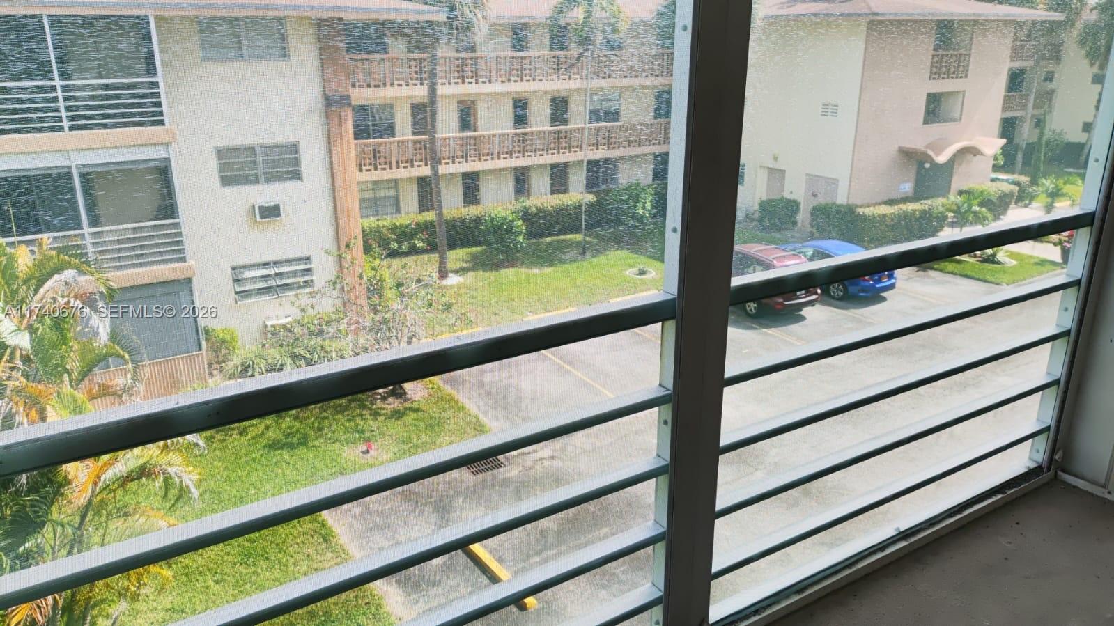 A view from a screened balcony overlooks a parking lot and apartment buildings — 17090 NE 14th Ave # 314, Miami FL 33162, MIAMI, FL