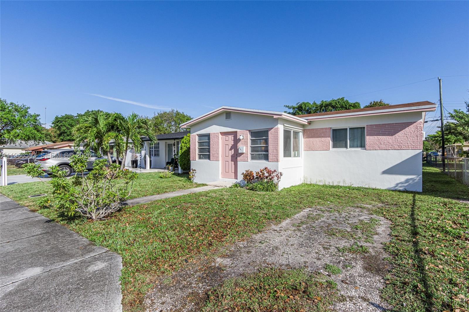 A single-story house with white and pink exterior walls sits behind a grassy front yard — 616 NW 3rd Ct, Hallandale Beach FL 33009, HALLANDALE BEACH, FL