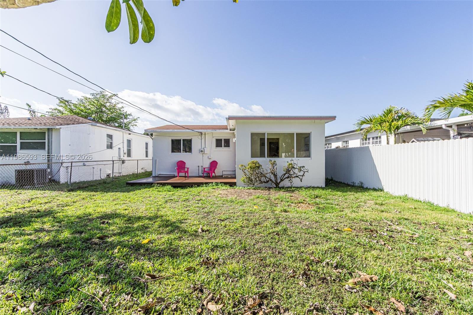 The backyard of a house features a wooden deck with two pink chairs — 616 NW 3rd Ct, Hallandale Beach FL 33009, HALLANDALE BEACH, FL
