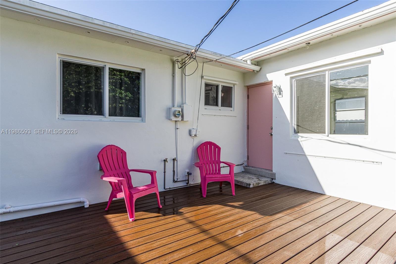 Two bright pink chairs sit on a wooden deck outside a white house — 616 NW 3rd Ct, Hallandale Beach FL 33009, HALLANDALE BEACH, FL