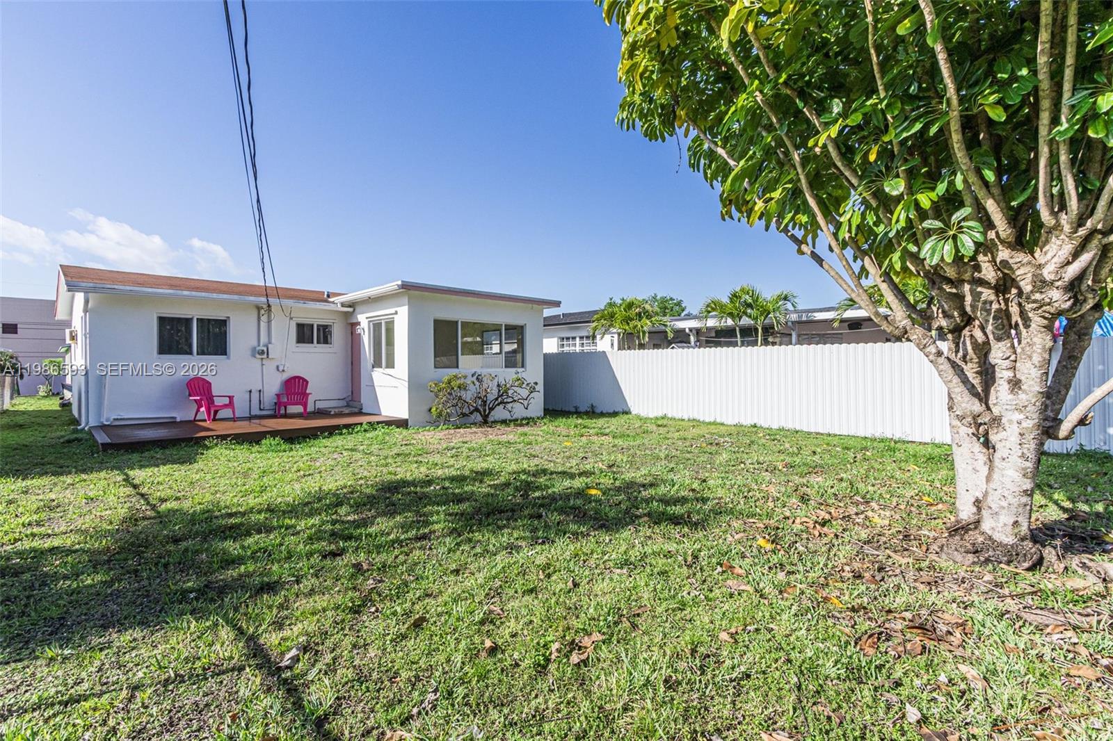 A white house with a wooden deck and two pink chairs sits in a yard — 616 NW 3rd Ct, Hallandale Beach FL 33009, HALLANDALE BEACH, FL