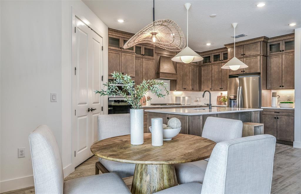 A dining area with a round wooden table sits in front of a modern kitchen — 13710 BROOKSIDE HAVEN STREET, RIVERVIEW, FL