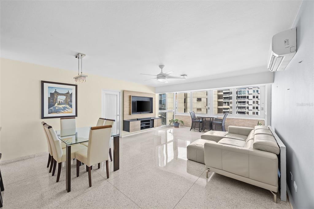 A bright, open-concept living and dining area features white tile floors, a sectional sofa, and balcony — 4429 AVE. ISLA VERDE UNIT 1103, CAROLINA, PR