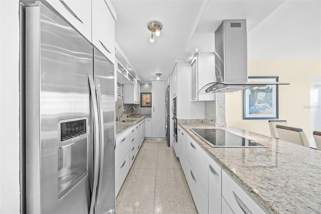 A modern galley kitchen features white cabinets, granite countertops, and stainless steel appliances — 4429 AVE. ISLA VERDE UNIT 1103, CAROLINA, PR