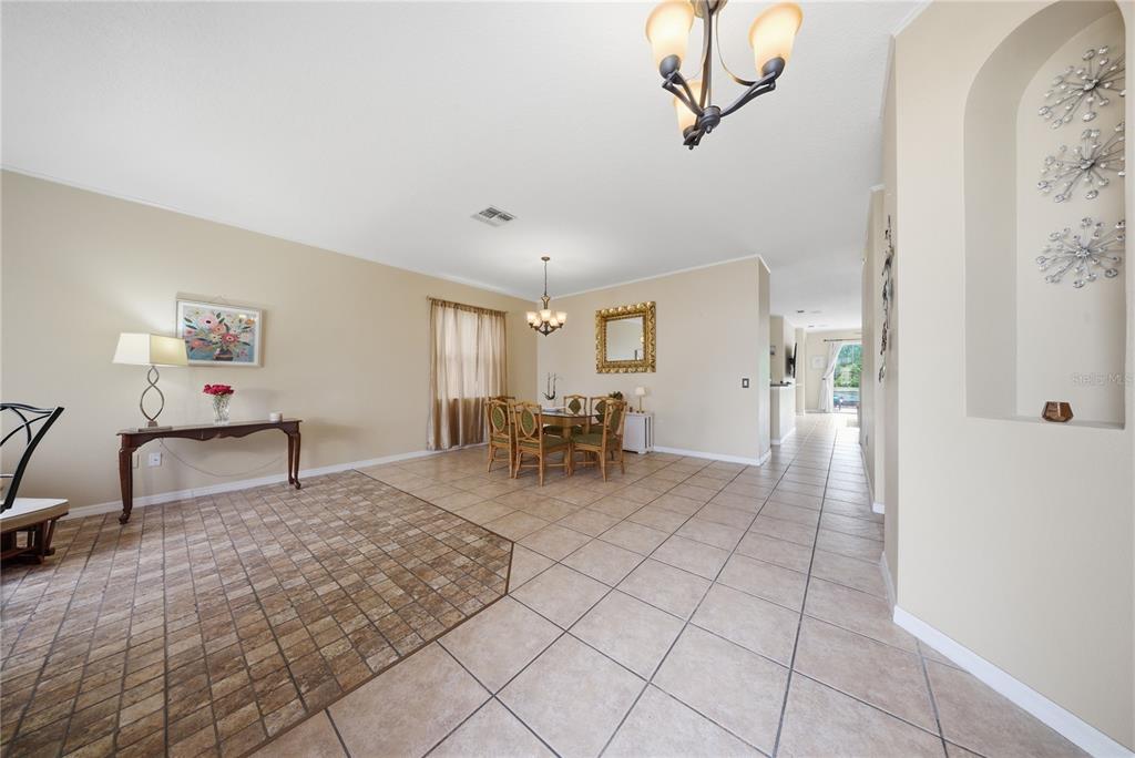 A dining area with tile floors, a chandelier, and a console table in an open room — 831 WHISPERING CYPRESS LANE, ORLANDO, FL