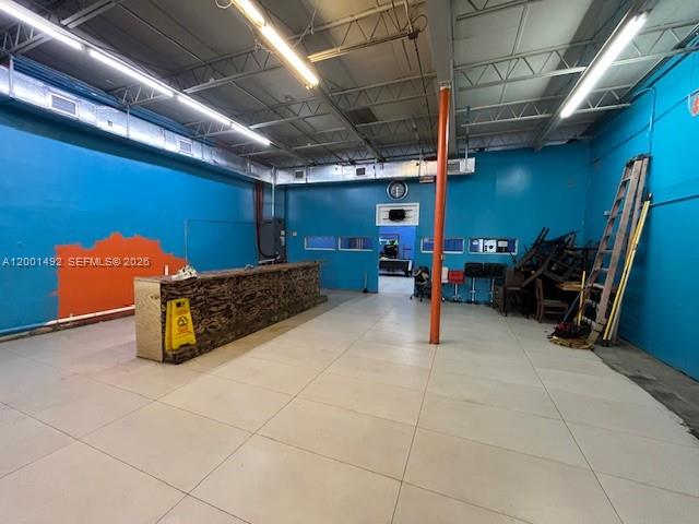 An open commercial space features bright blue walls, a wooden bar, and a tall ladder — 1120 E 25th St, Hialeah FL 33013, HIALEAH, FL