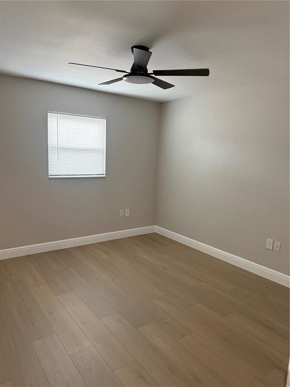 An empty bedroom features light-colored wood-look flooring, gray walls, and a ceiling fan — 7350 LANDMARK DRIVE, SPRING HILL, FL