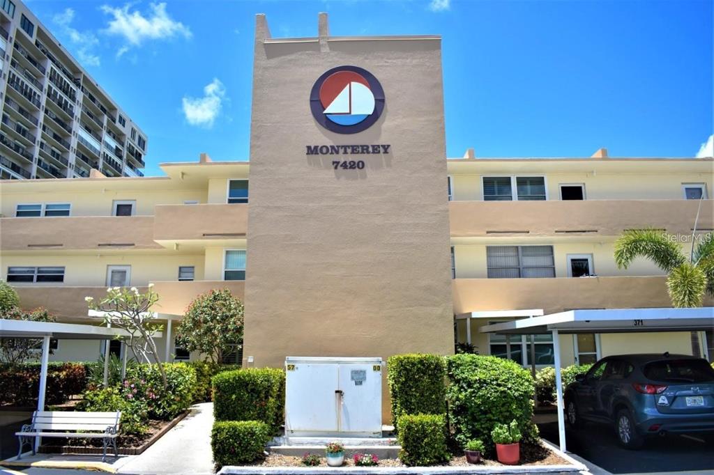A tan multi-story apartment building features a central tower with a sailboat logo — 7420 BAY ISLAND DRIVE S UNIT 176, SOUTH PASADENA, FL
