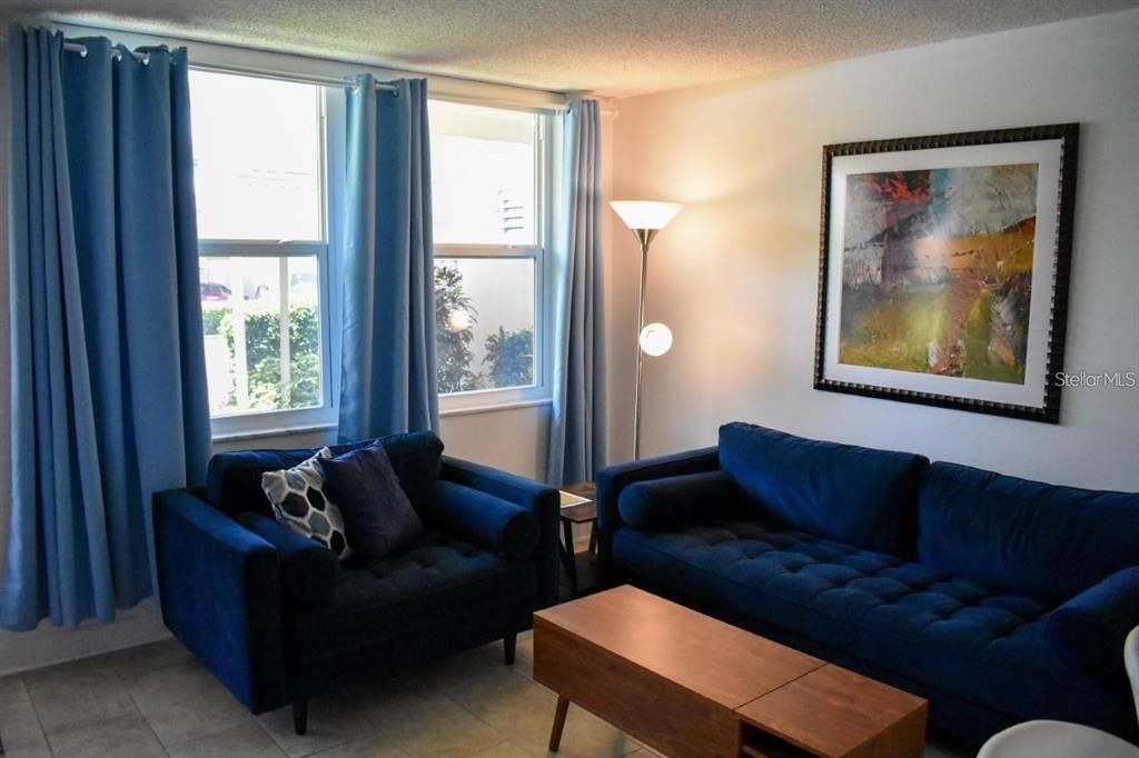 A living room features blue sofas, a wooden coffee table, and blue curtains over windows — 7420 BAY ISLAND DRIVE S UNIT 176, SOUTH PASADENA, FL