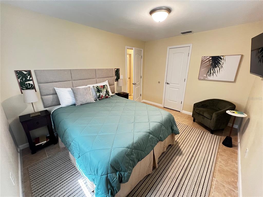 A bedroom features a bed with a gray headboard, a green chair, and a rug — 138 WOODS ROAD, SAN MATEO, FL