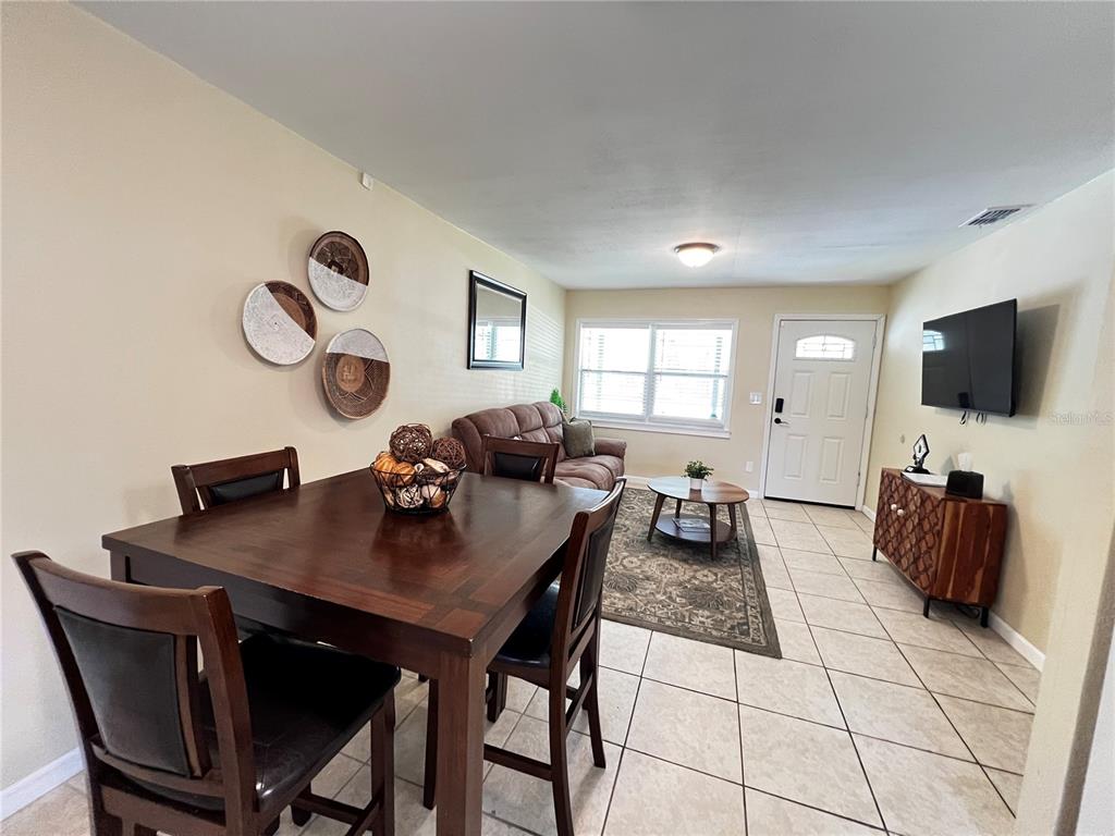 A dining area with a dark wood table leads into a living room with tile flooring — 138 WOODS ROAD, SAN MATEO, FL