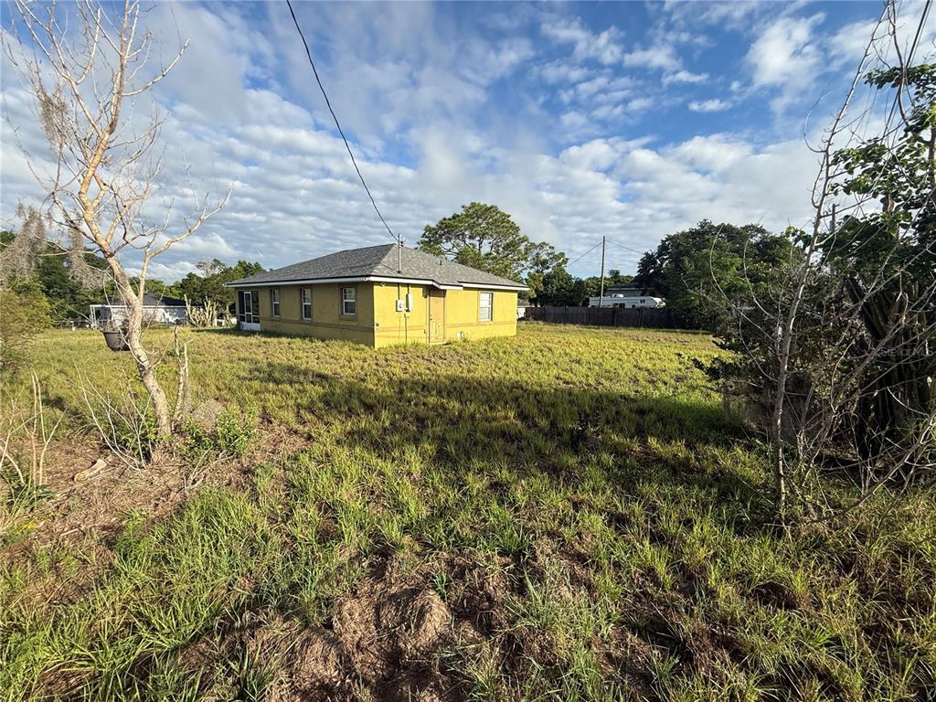 A yellow single-story house sits on a large, grassy lot under a cloudy sky — 202 OWENS ROAD, LAKE WALES, FL