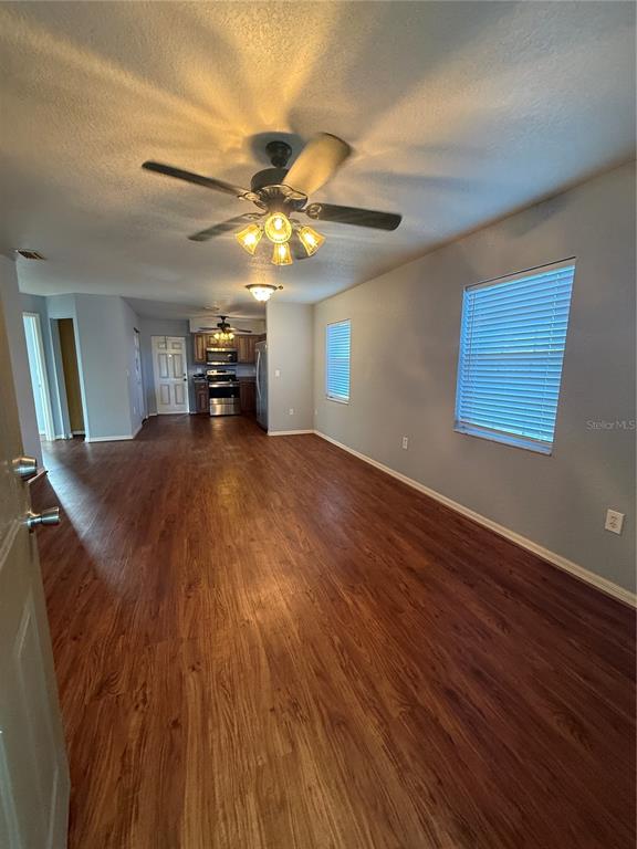 A view of a living area with wood-look flooring, a ceiling fan, and a kitchen — 202 OWENS ROAD, LAKE WALES, FL