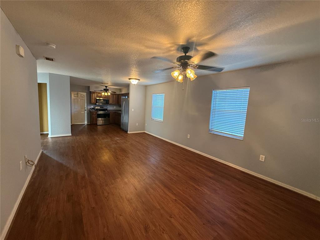 An open-concept living area with wood-look flooring leads to a kitchen with dark cabinets — 202 OWENS ROAD, LAKE WALES, FL