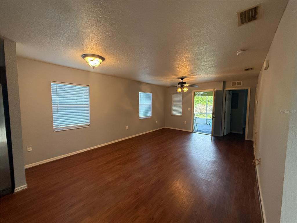 An empty living room features wood-look flooring, light gray walls, two windows, and a ceiling fan — 202 OWENS ROAD, LAKE WALES, FL