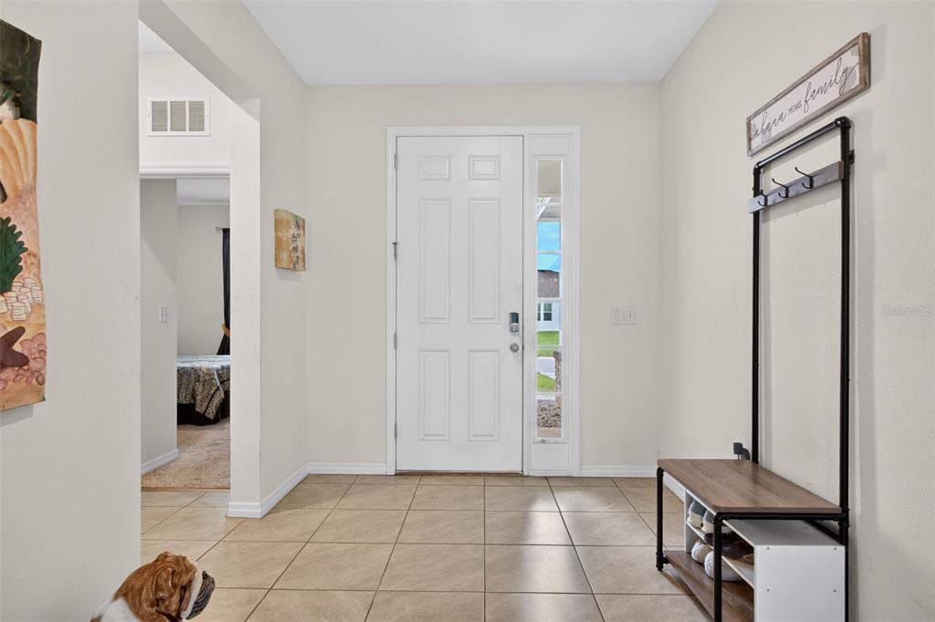 An entryway features a white front door, tile flooring, and a coat rack with bench — 13454 GOLDEN LIME AVENUE, SPRING HILL, FL