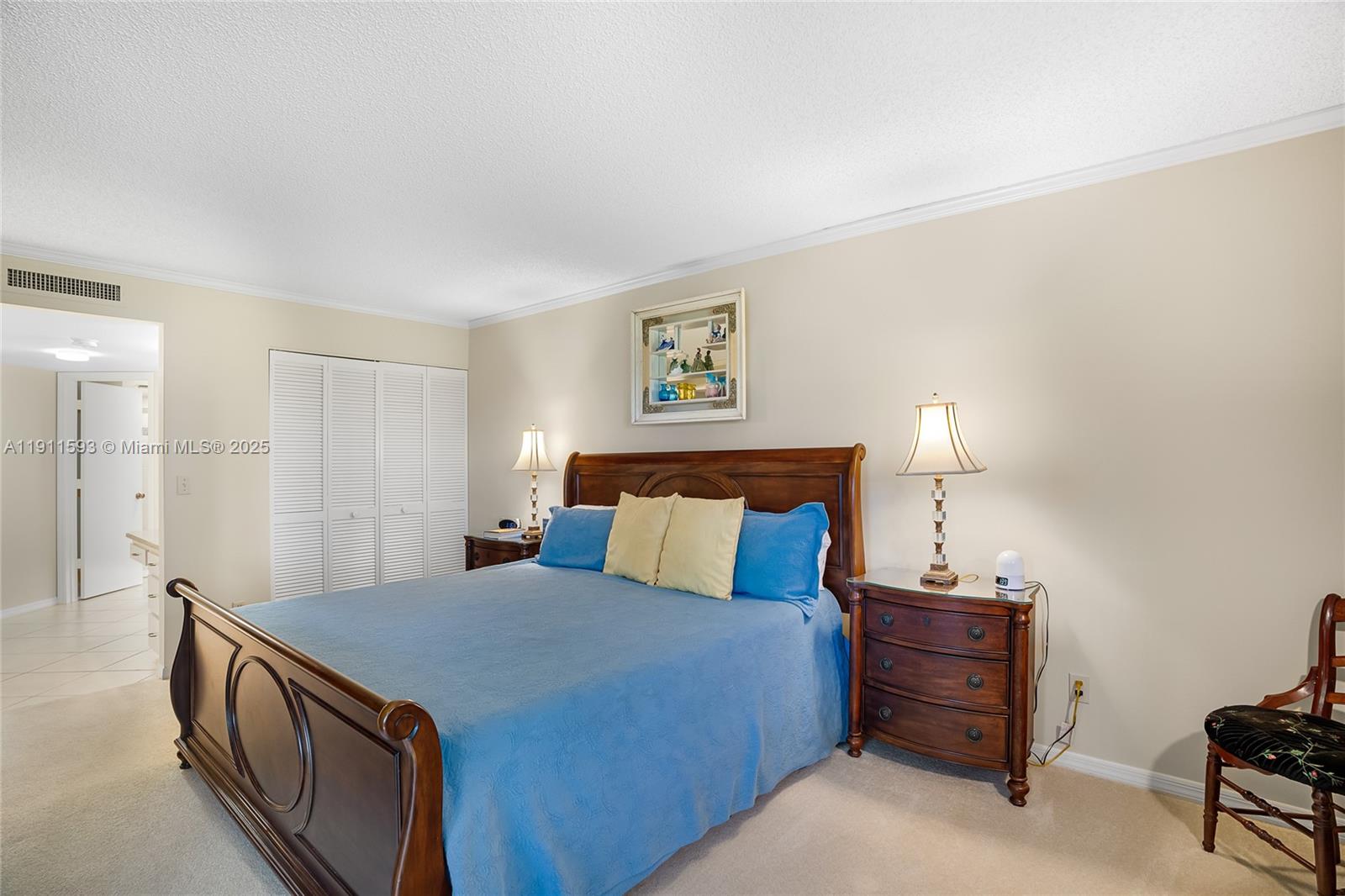 A bedroom features a wooden bed frame, blue bedding, two nightstands with lamps, and carpet — 1815 Mooringline Dr # 1, Vero Beach FL 32963, VERO BEACH, FL