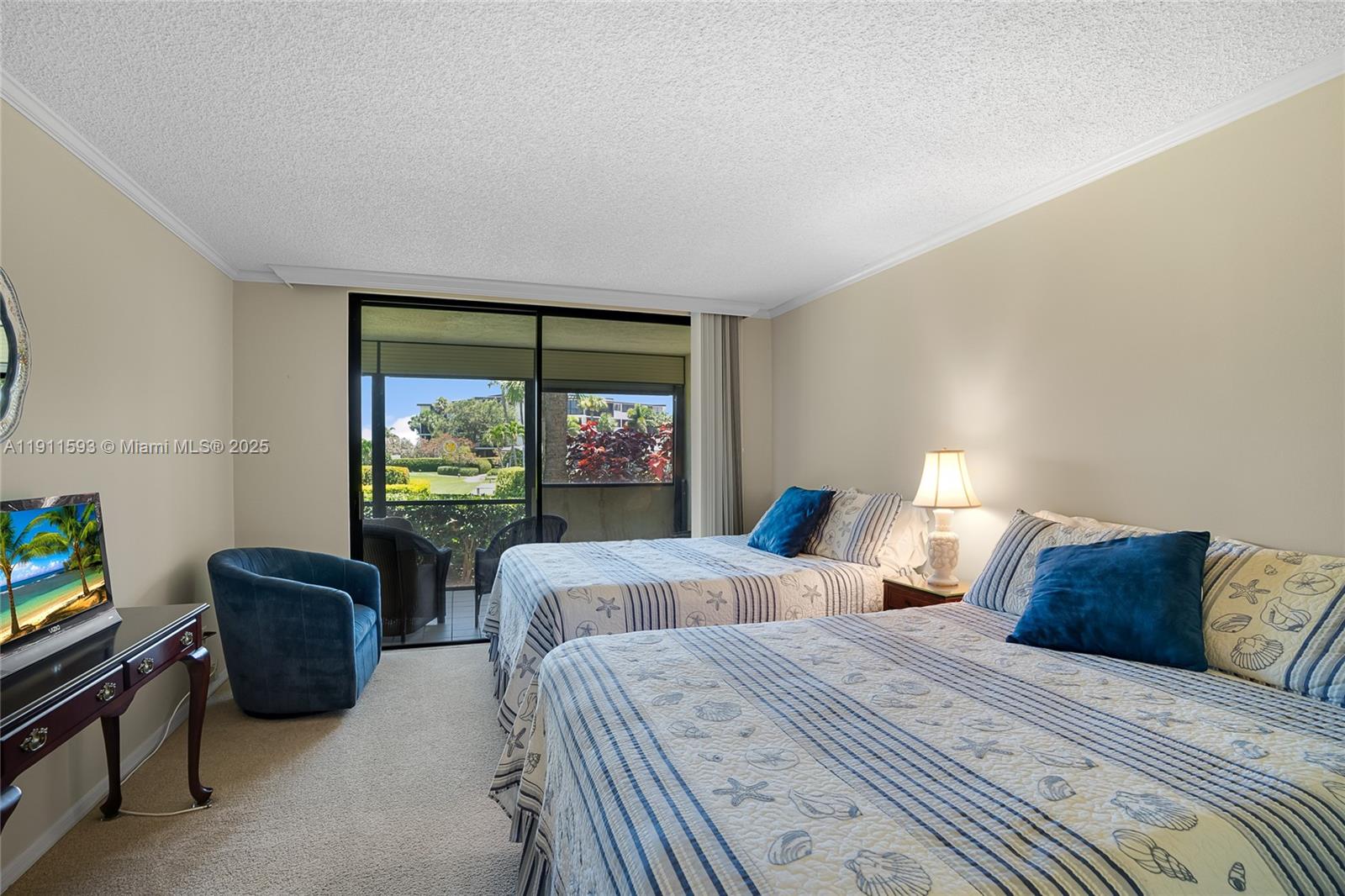 A bedroom with two beds, a blue armchair, and a sliding door to a balcony — 1815 Mooringline Dr # 1, Vero Beach FL 32963, VERO BEACH, FL